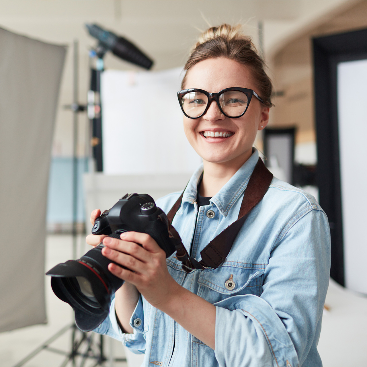 Bild på en ung fotograf som håller i en kamera när hon ler